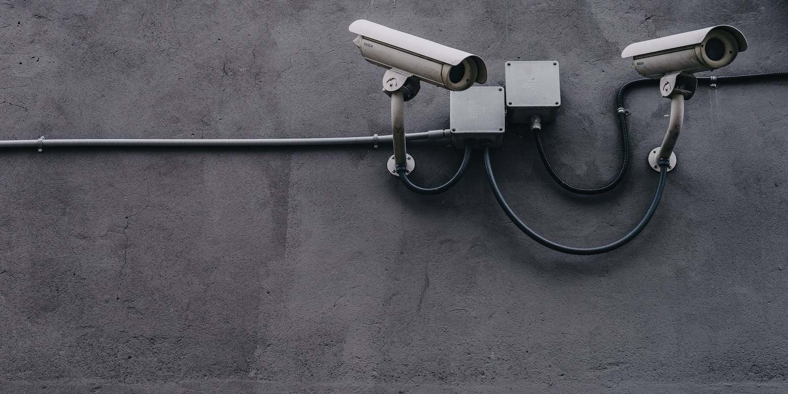 two bullet surveillance cameras attached on wall